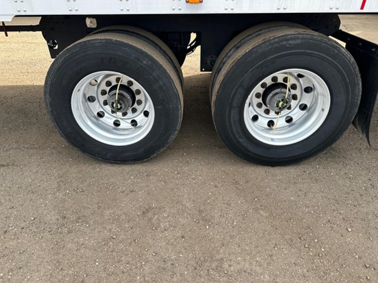 Trailer dual rear wheels showing steel rims and tires, part of a refrigerated Utility 3000R trailer. Nearby frame and suspension components visible.