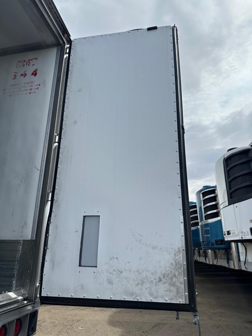 Trailer side door panel of a 2022 Utility 3000R trailer showing a vertical rectangular access patch and riveted edges.
