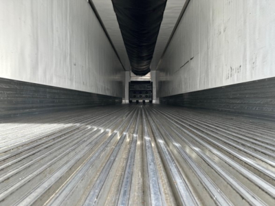 Trailer interior with ribbed metal floor, nose-to-back view showing ceiling ducts and side walls; empty cargo space of a reefer trailer.