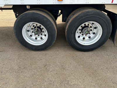 Trailer dual rear wheels showing steel rims and tires, part of a refrigerated Utility 3000R trailer. Nearby frame and suspension components visible.