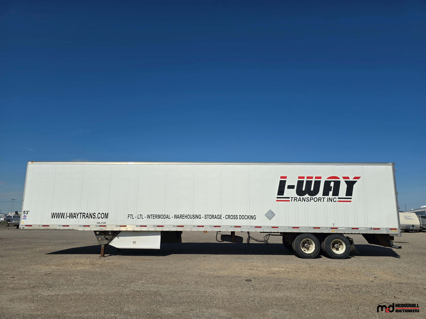 Trailer side showing 53' tandem dry van box with I-Way Transport logo and text on white surface, under clear blue sky.