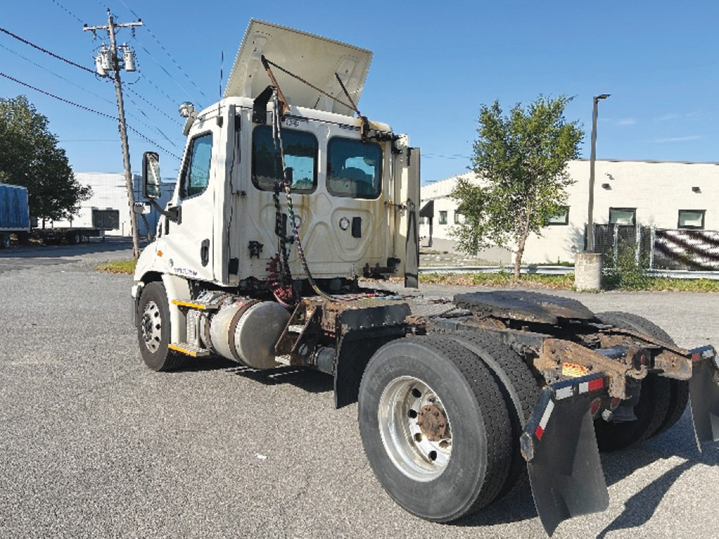 Truck cab and chassis of a Freightliner Cascadia 113 from a side/rear view. Front of cab with raised sleeper and exposed engine bay area. Visible tires, fifth wheel plate, and mudflaps.