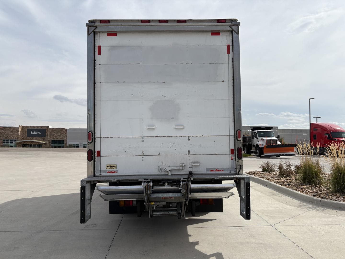 Isuzu NPR-HD rear view showing tailgate and bumper with reflective strips and hookups.