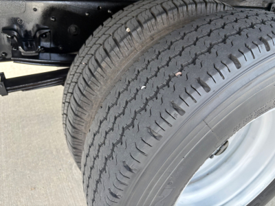 Isuzu NPR-HD truck undercarriage showing dual rear wheels and tire tread; chassis and suspension components visible.