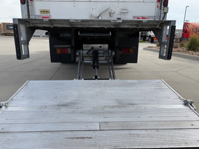 Isuzu NPR-HD rear view showing lift or ramp mechanism and metal platform at tail with hitch and surrounding chassis components.