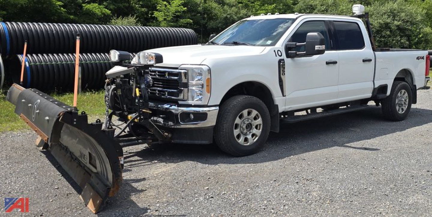 Ford F-350 Super Duty XLT Crew Cab with plow attached in a gravel lot.