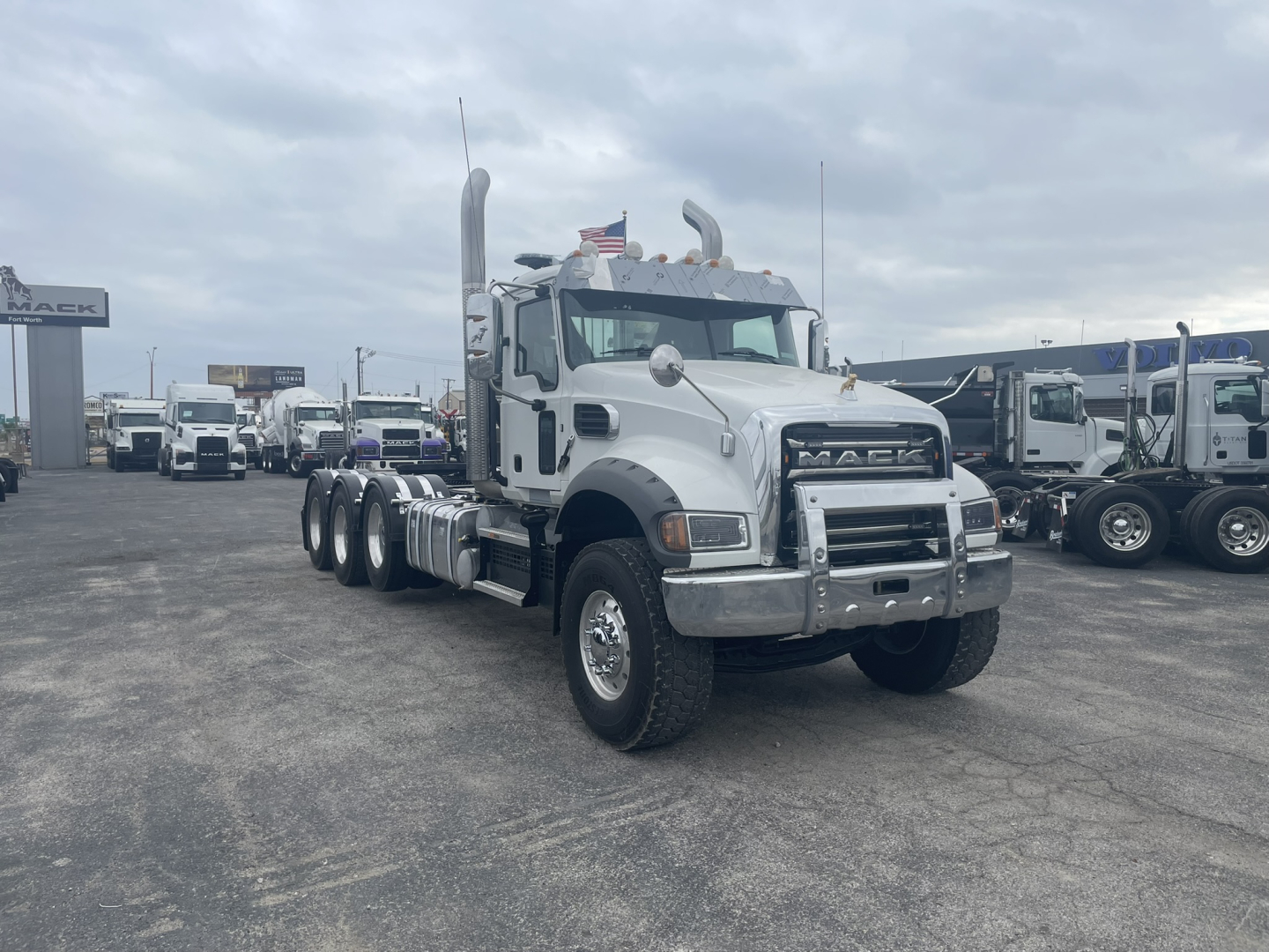 Mack GR84FT conventional daycab truck showing chrome front bumper and dual exhaust in a truck lot.