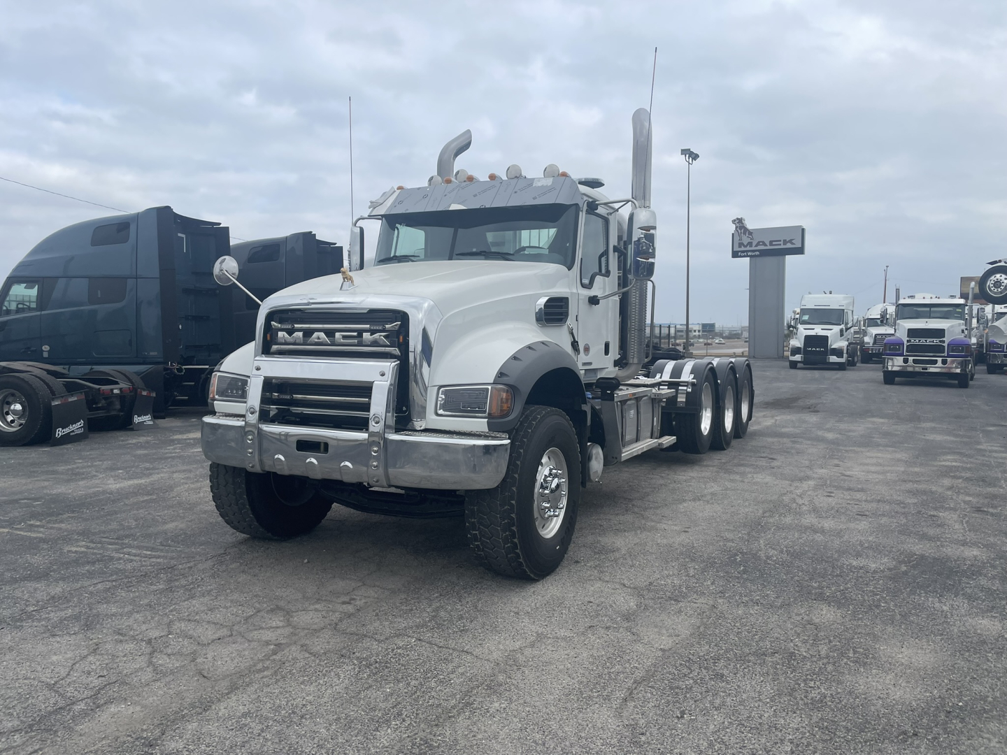 Mack GR84FT conventional daycab truck in white, front view showing chrome bumper and grille, dual rear axles, daytime running gear.