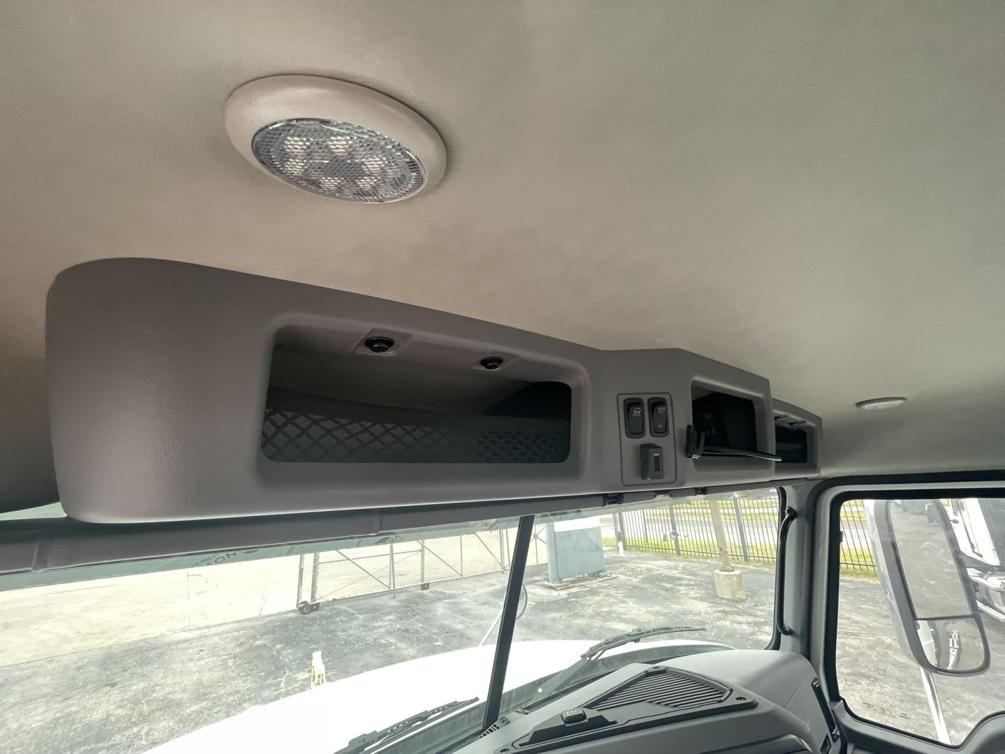 Cab interior overhead console with storage compartments and a speaker in the ceiling of a Mack truck cab.