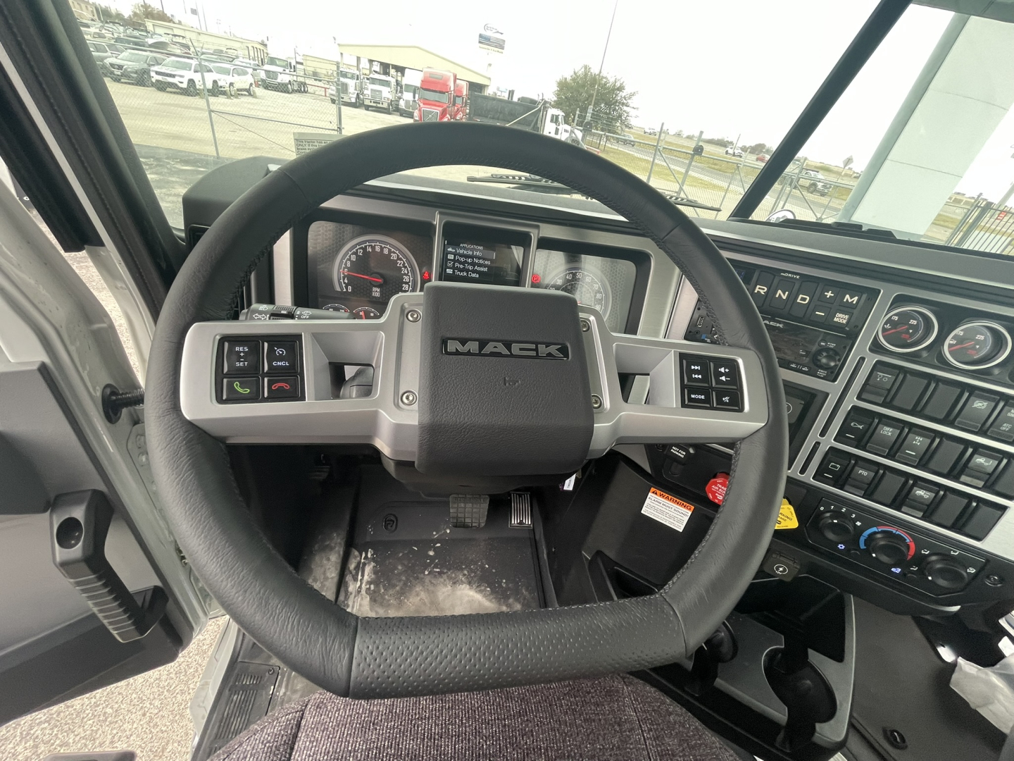 Mack GR84FT truck interior showing steering wheel, dashboard, and instrument cluster from driver’s seat.