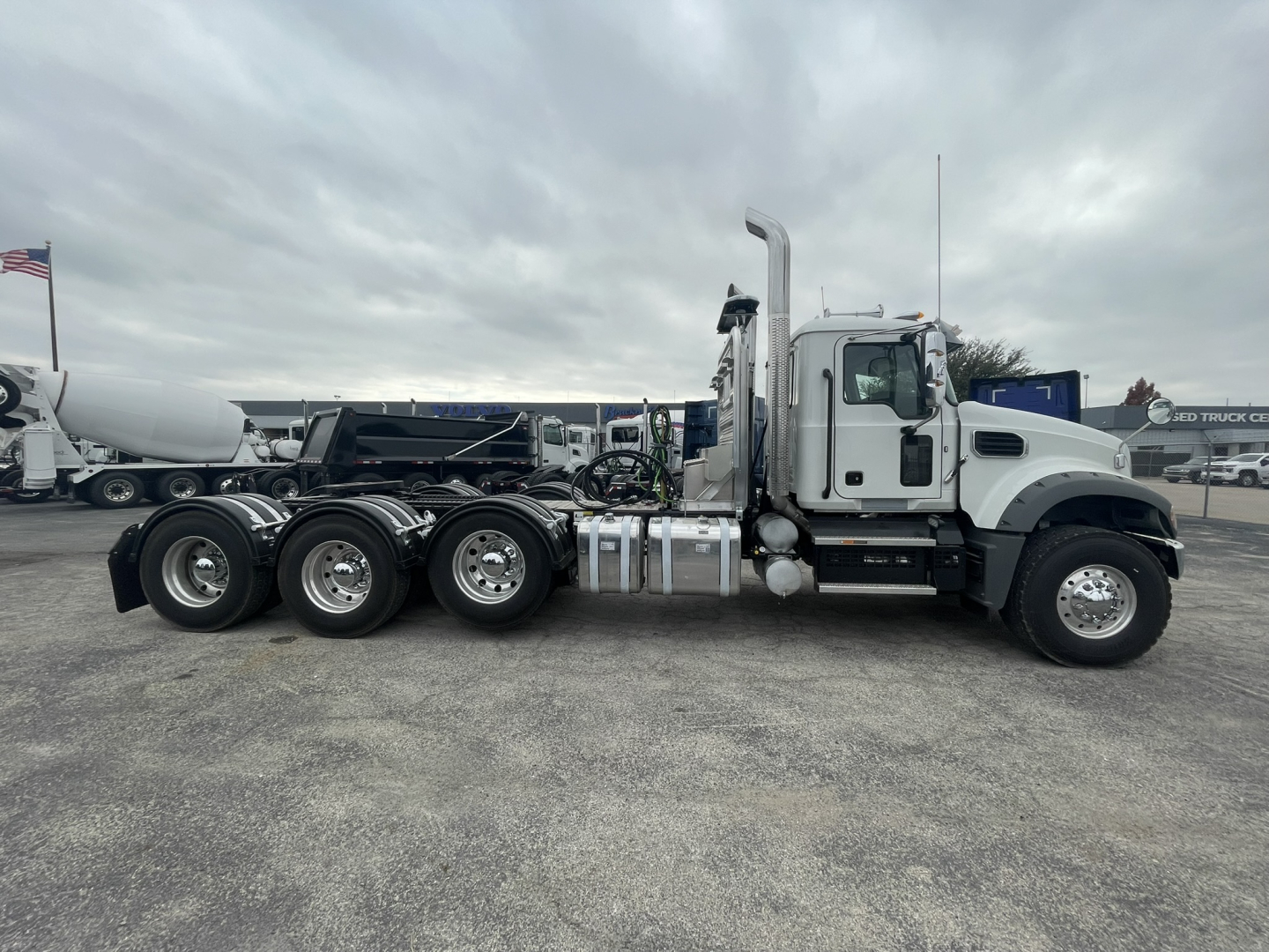 Conventional Daycab truck in side view showing 6-wheel rear axle configuration, fuel tanks, exhaust stack, and Mack GR84FT cab.
