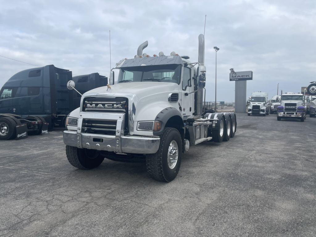 Mack GR84FT conventional daycab truck in white, front view showing chrome bumper and grille, dual rear axles, daytime running gear.