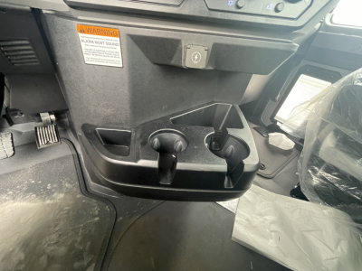 Cab interior of a new Mack GR84FT showing dual cup holders and a small storage slot near the driver footwell area.