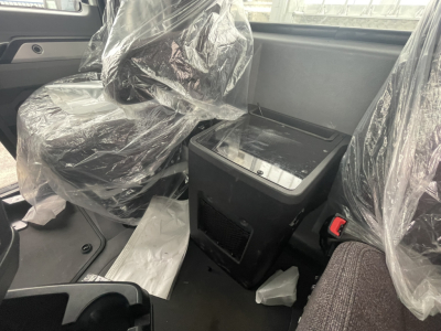 Mack GR84FT cab interior showing driver and passenger seats wrapped in plastic, center console, and dashboard area.
