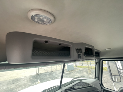 Cab interior overhead console with storage compartments and a speaker in the ceiling of a Mack truck cab.