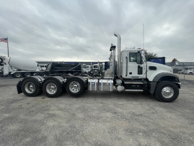 Conventional Daycab truck in side view showing 6-wheel rear axle configuration, fuel tanks, exhaust stack, and Mack GR84FT cab.