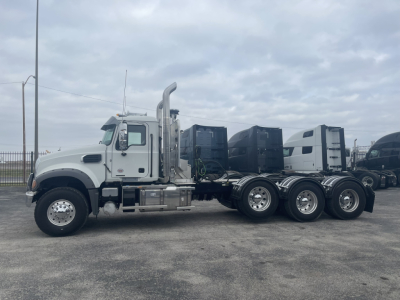 Mack GR84FT truck tractor side view showing three rear axles, chrome exhaust stacks, and fuel tanks.