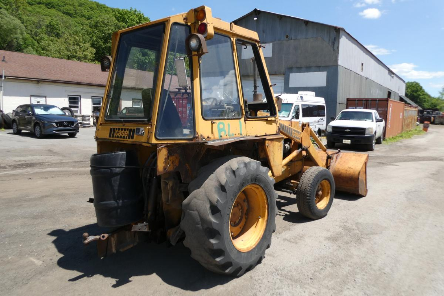 Case 480C loader with bucket attachment, side view showing worn yellow paint and glass cab, in an outdoor lot.