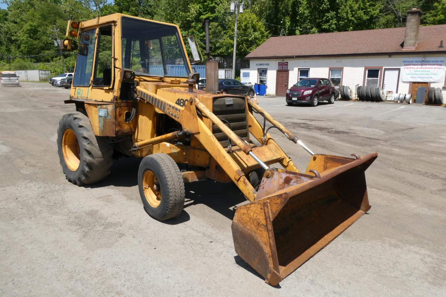 Case 480C loader with front bucket attachment and yellow paint, side view in a parking lot.