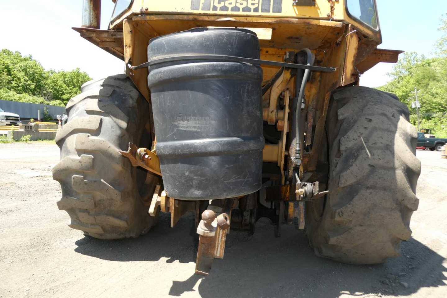 Case 480C loader rear view showing large tires, exhaust stack, black cylindrical air cleaner canister, and hitch area.