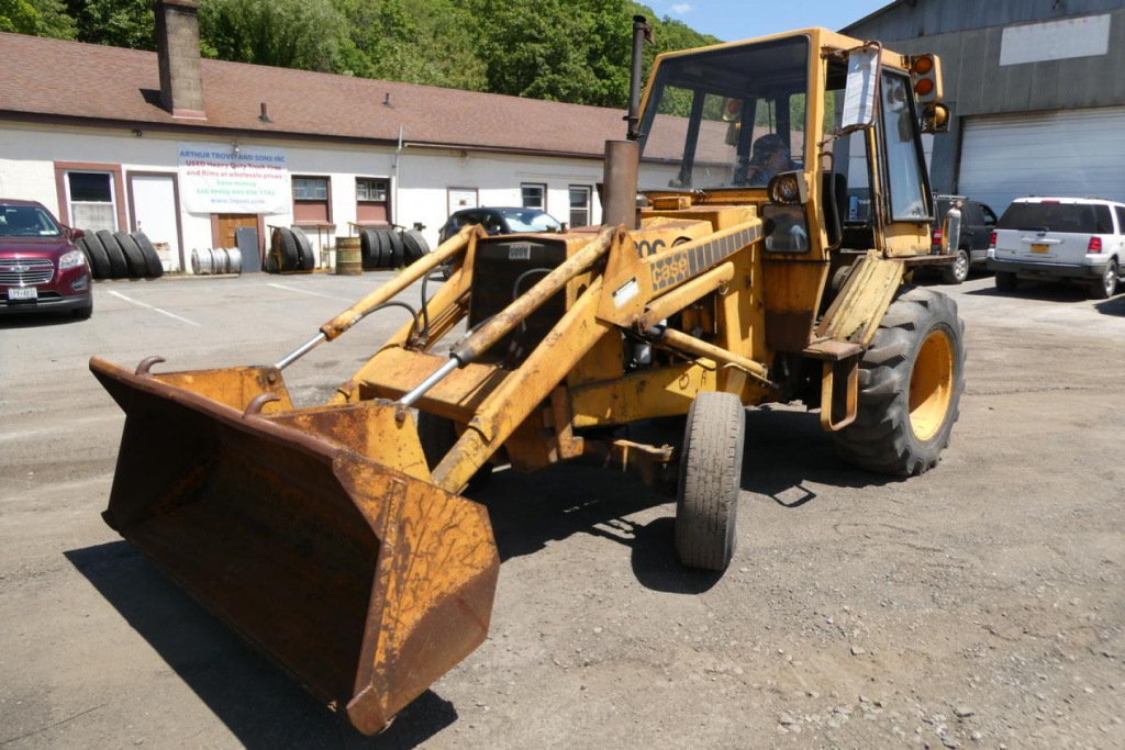 Front-left view of a yellow 1979 Case 480C loader with a large rusted bucket attached, in-service, with hydraulic arms and cabin, outdoor lot.