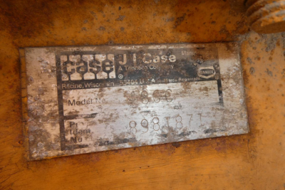 Machine nameplate showing Case logo and model information with scratched text, serial/ID numbers on orange metal surface.