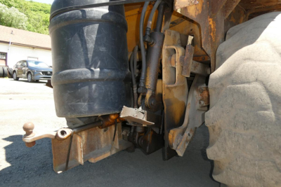 Case 480C loader rear view showing hitch, hydraulic hoses, and large rear wheel with mud and dust accumulated.