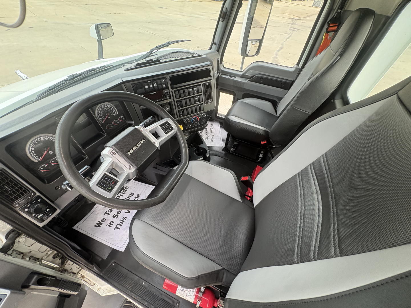 Truck cab interior showing steering wheel, dashboard, and driver's seat of a 2022 Mack AN42T conventional daycab.
