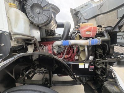 Mack AN42T engine bay showing cooling system hoses, coolant reservoir, air intake, and engine block with red paint accents.