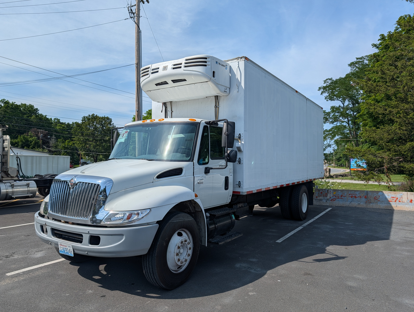 2006 International 4300 box truck with a refrigeration unit on top, angle view in parking lot.