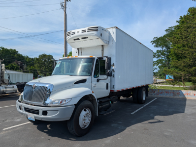 2006 International 4300 box truck with a refrigeration unit on top, angle view in parking lot.