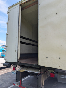 Box truck rear with open cargo door showing empty interior and loading platform.