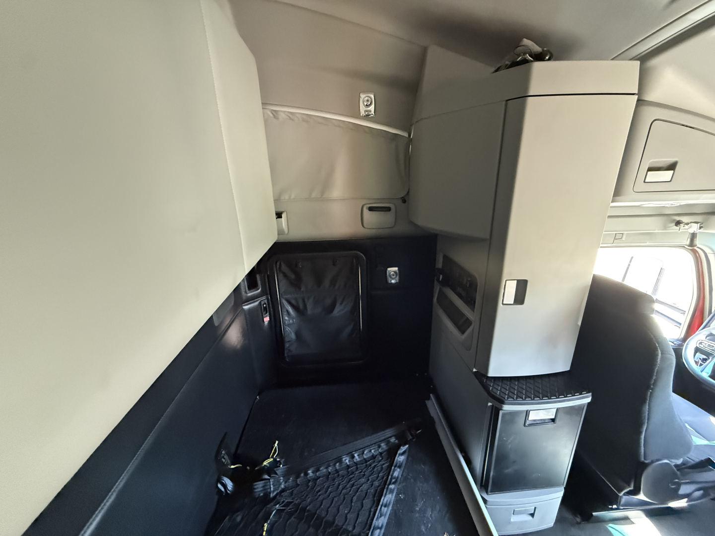 Interior cab storage and bunk area of a 2023 Kenworth T680 sleeper truck showing storage cabinet, drawers, and overhead compartments.