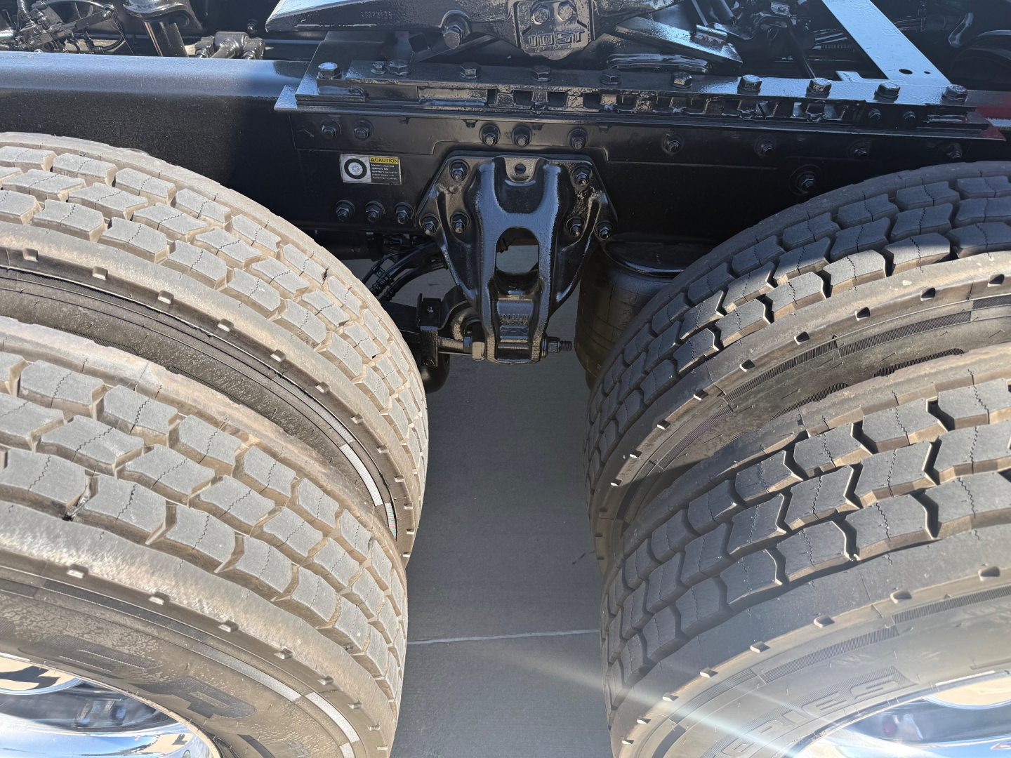 Kenworth T680 chassis view showing dual rear axles and fifth wheel area with undercarriage components visible.