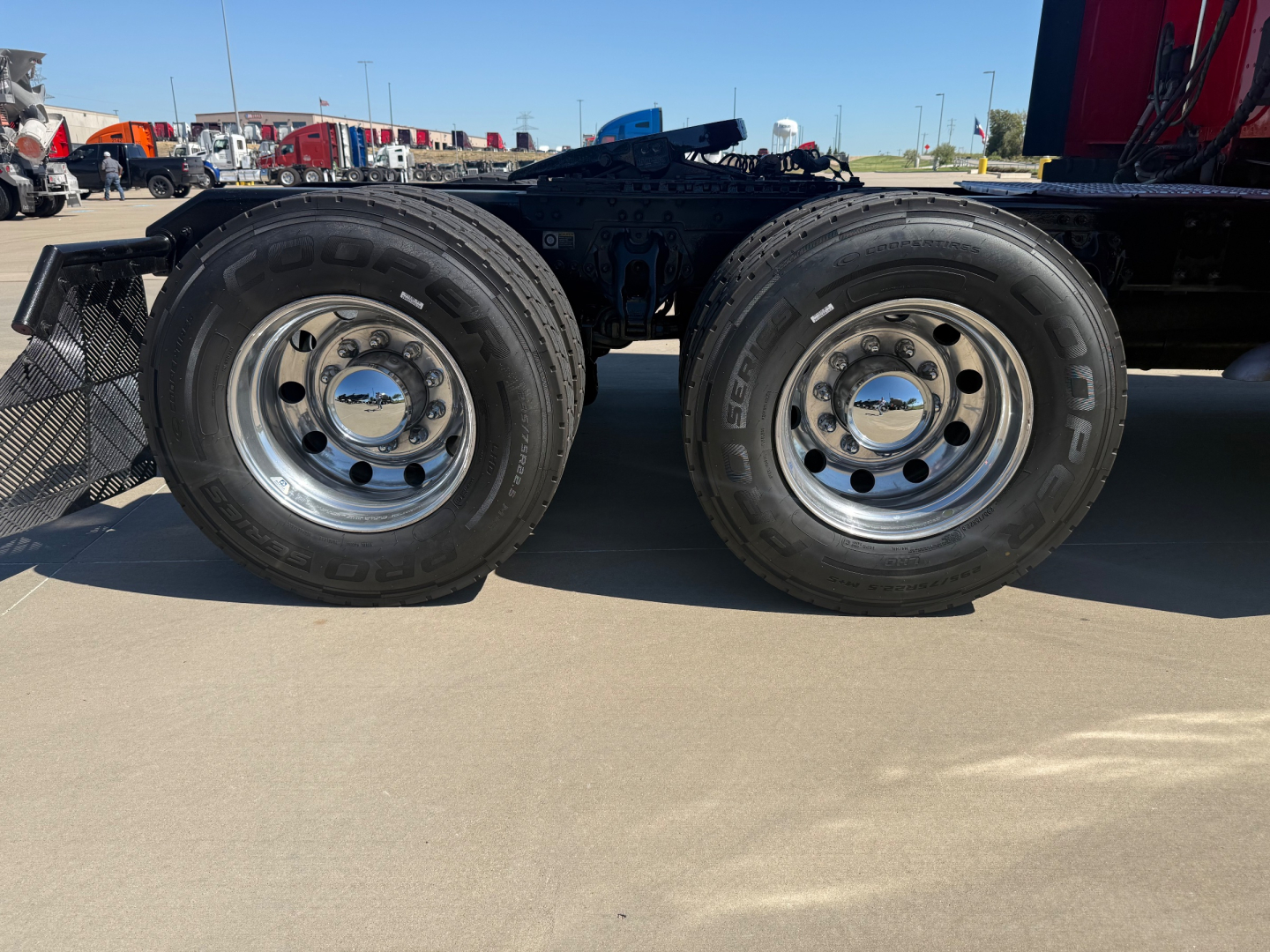 Dual rear tires on a Kenworth truck chassis with polished wheels and rims visible.