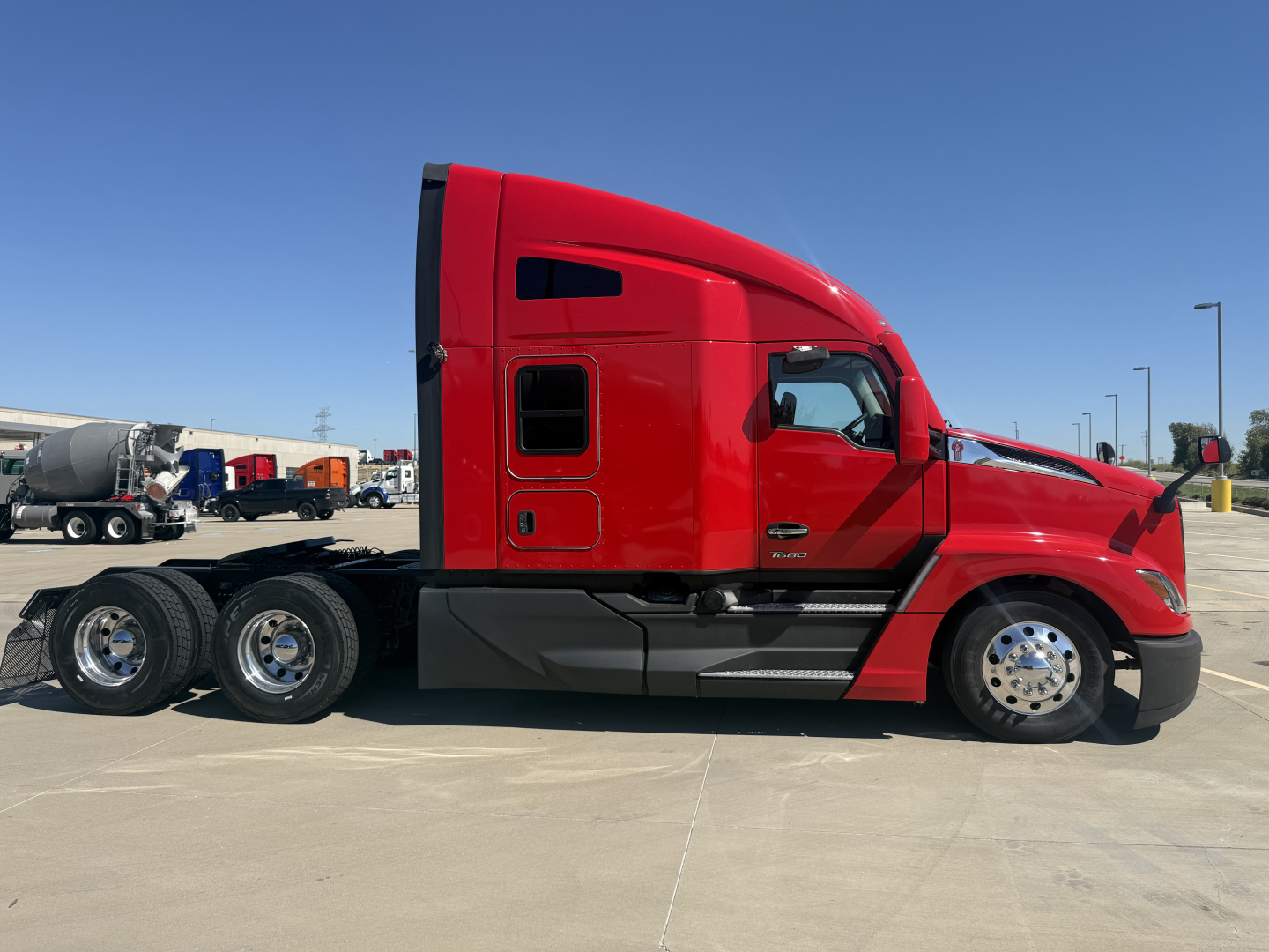 Kenworth T680 semi-truck side profile showing red cab and attached chassis with three rear axles.