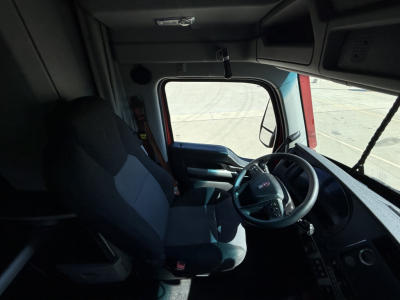 Kenworth T680 cab interior showing steering wheel and driver seat with dashboard and window view.