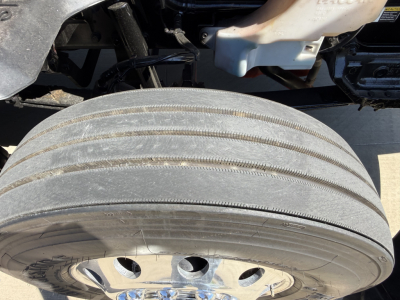 Kenworth T680 wheel and tire view showing dual rear axle drum hub and surrounding undercarriage components