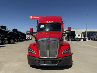 Kenworth T680 truck front view showing large chrome grille and red cab, daytime at dealership lot.