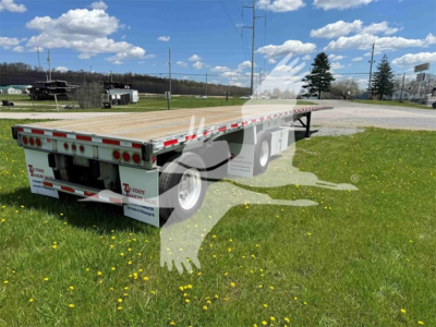 Flatbed trailer with wooden deck and dual rear axles showing Reflective tape and rear lights.