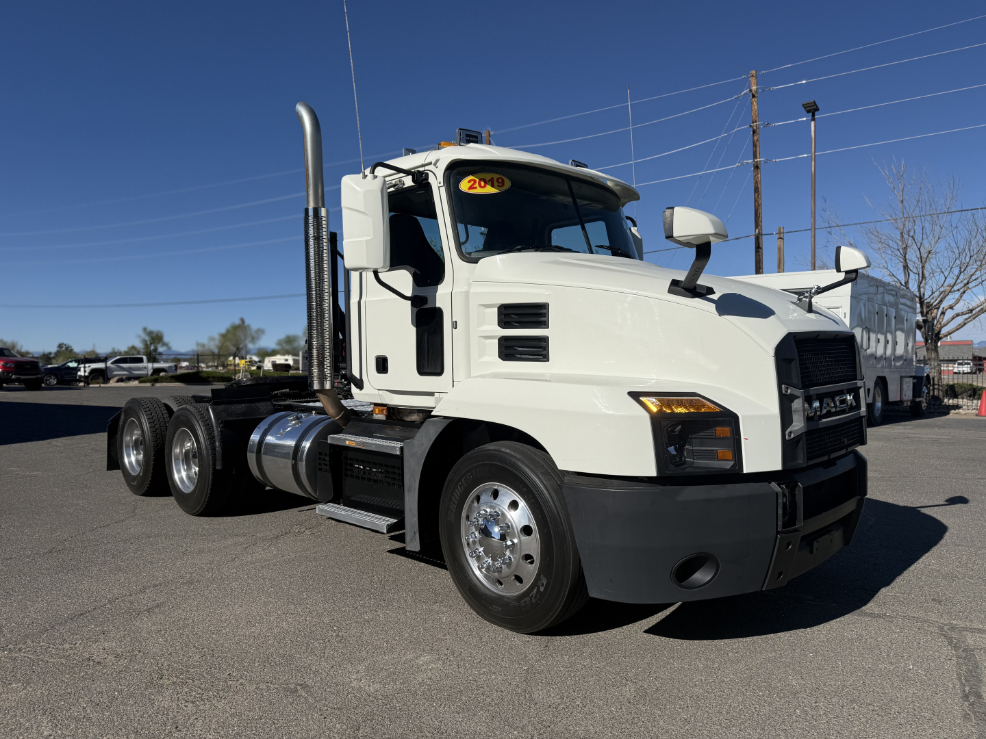 2019 Mack Anthem conventional daycab truck side/front view showing cab, long chassis, dual rear axles, chrome wheels, fuel tanks, and exhaust stack.