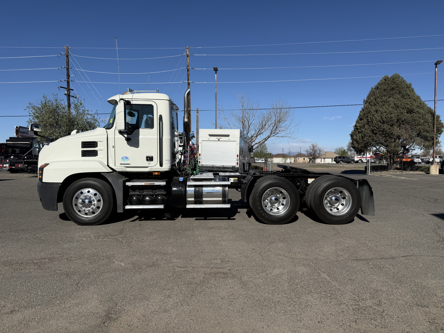 Truck side view of a white 2019 Mack Anthem conventional daycab, showing cab, fuel tanks, and dual rear axles with chrome wheels.