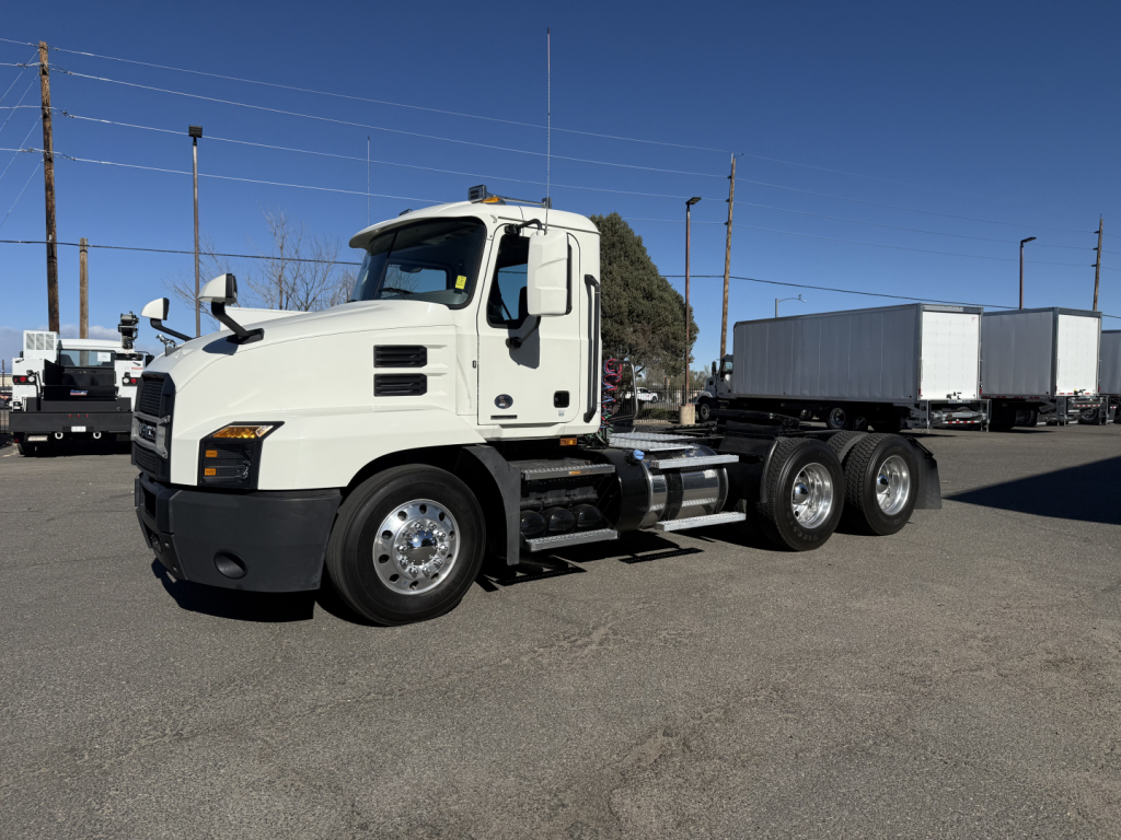Truck showing 2019 Mack Anthem daycab with white cab and attached trailer in a dealership lot.