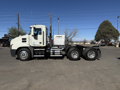 Truck side view of a white 2019 Mack Anthem conventional daycab, showing cab, fuel tanks, and dual rear axles with chrome wheels.