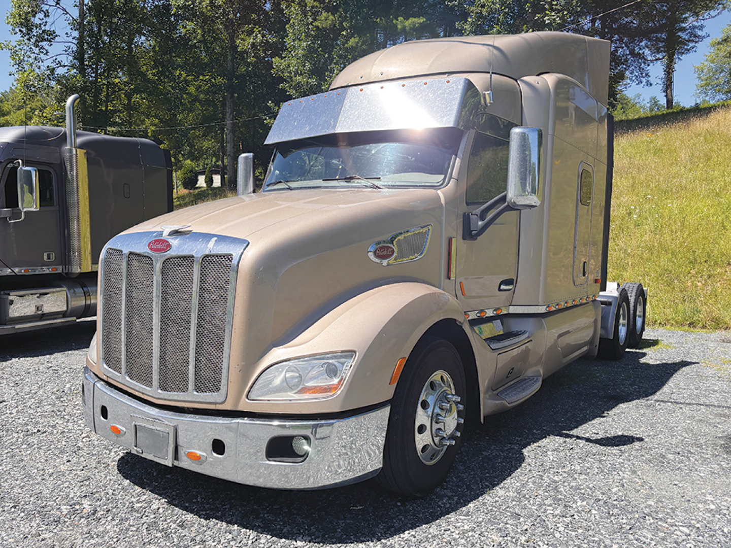 Peterbilt 579 UltraCab semi-truck front-left view showing chrome grille, beige exterior, day cab with sleeper, dual rear axles, large mirrors.
