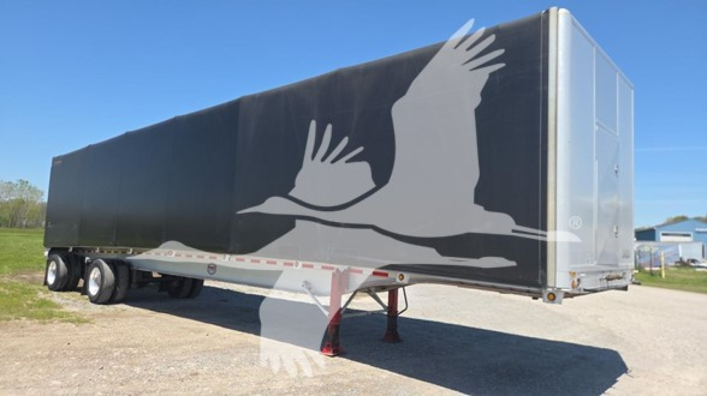 Trailer showing curtain side with large white bird graphic and silver front; side view with two axles and jack stand visible