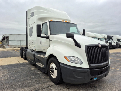 Truck shows white 2023 International LT625 conventional sleeper cab with black grille and dual rear axles, front view, VIN 3HSDZAPR4PN728950 visible near the bumper.