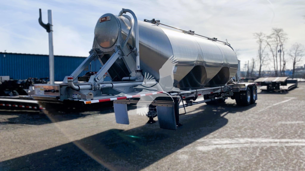 Heil cementer trailer in a parking lot, stainless steel cylindrical tank on a dual-axle trailer with rear hitch and supporting stands.