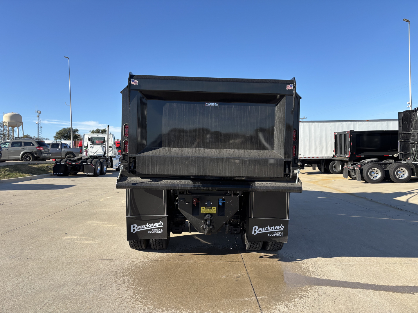 Dump truck bed of a new 2026 Mack PI64 rear view showing dump body and rear bumper with mud flaps and taillights.