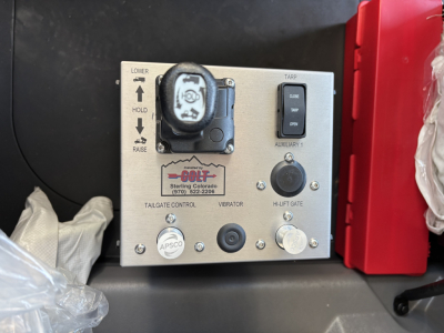 Mack PI64 cab interior showing gear shifter on control panel labeled Diamond Colorado? with buttons and switches; includes Tailgate Control, Vibrator, Aux power, and a red exterior panel nearby.